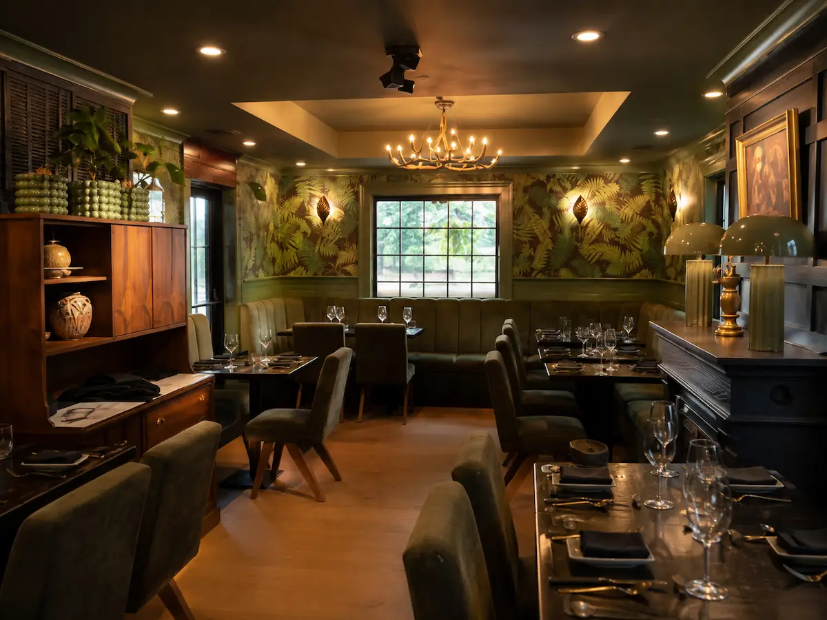 Warm dining room with green botanical décor and set tables